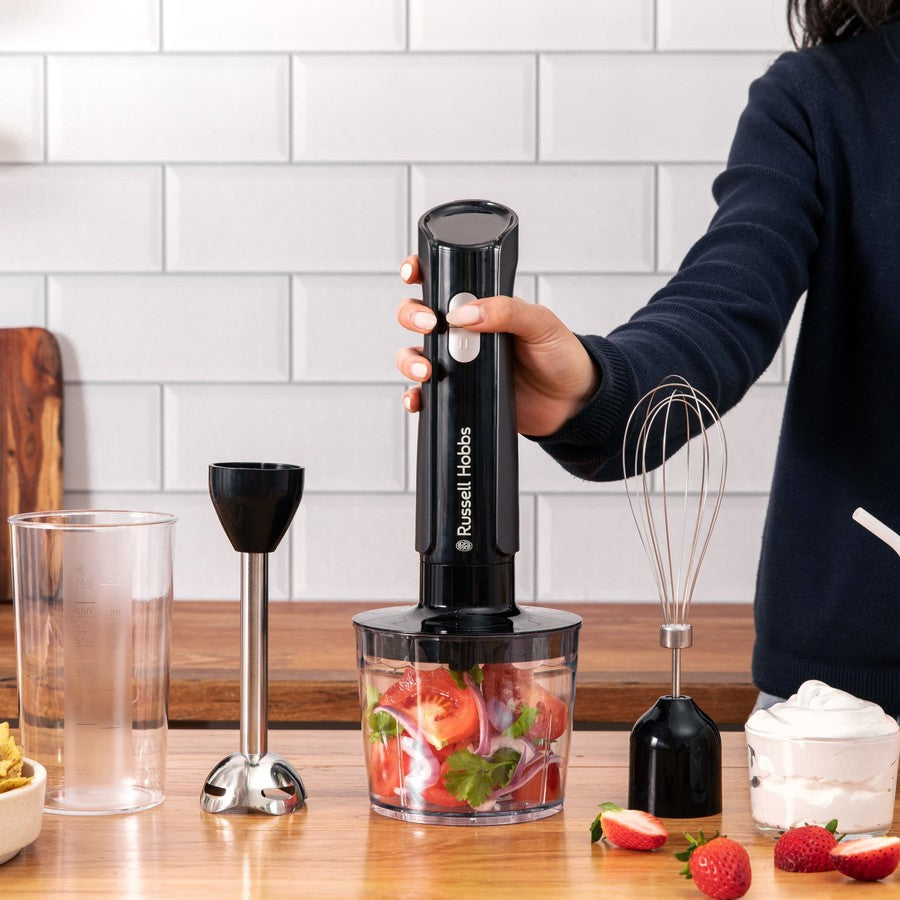 Person using a Russell Hobbs blender on a kitchen counter with ingredients and tools around.