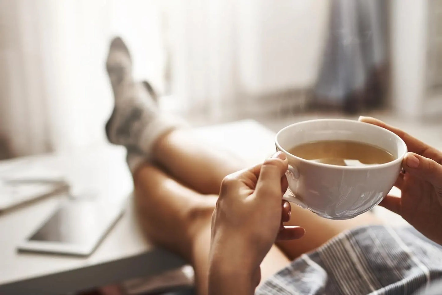 Person holding a cup of tea with a blurred background