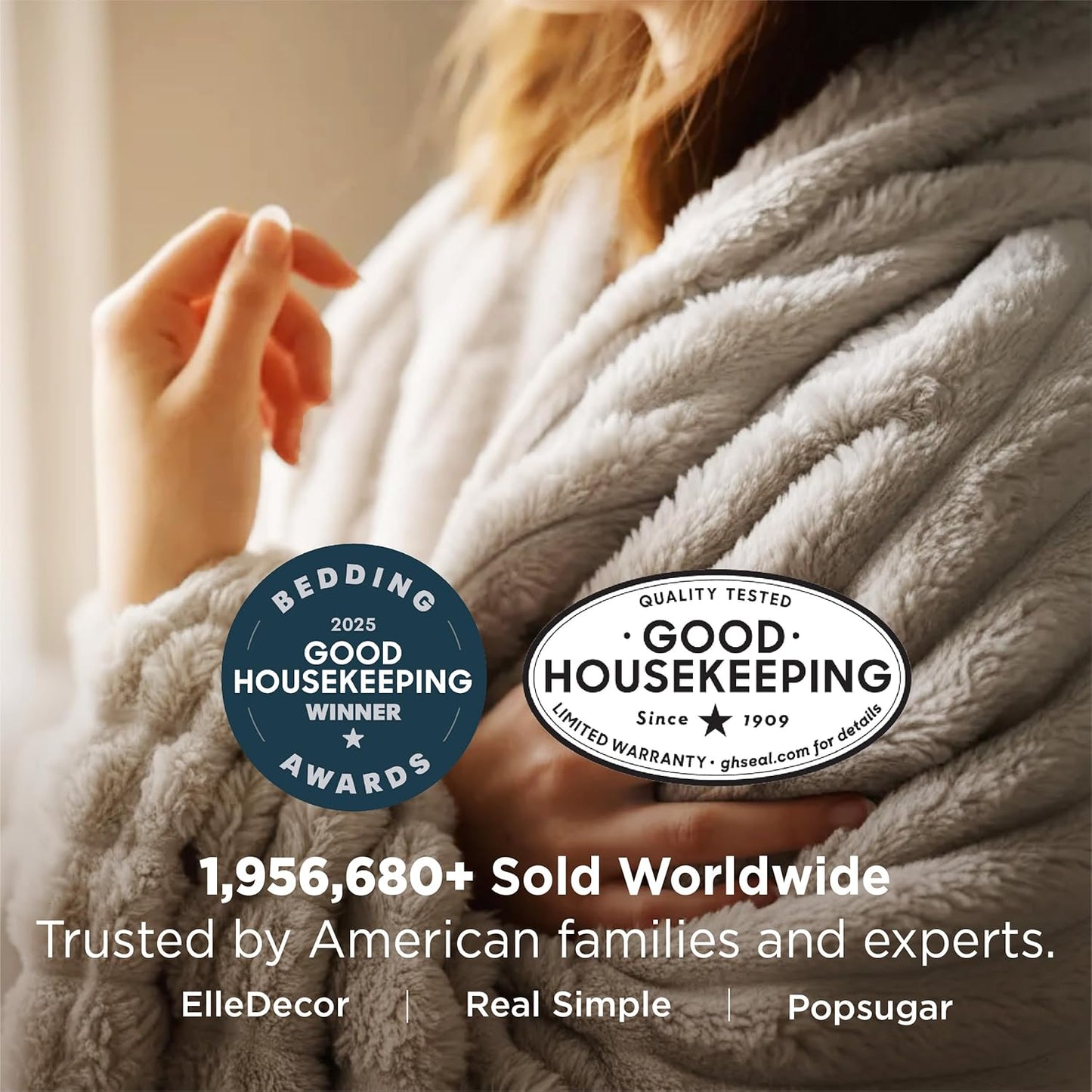 Person wrapped in a plush blanket with Good Housekeeping awards displayed.