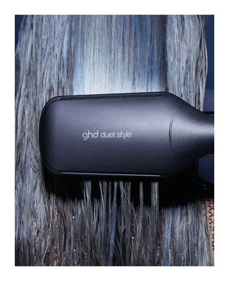 ghd duet style hair dryer on a textured surface with hair strands.