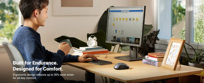 Person using a computer at a desk with ergonomic equipment, surrounded by books and decor.
