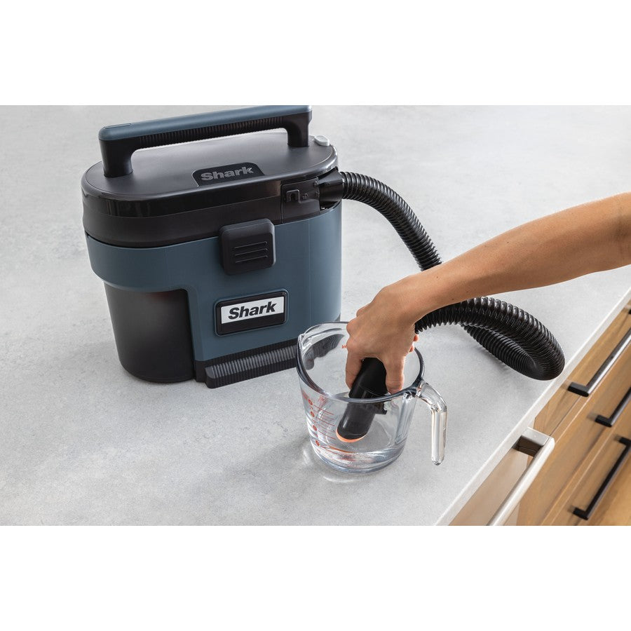 Shark vacuum cleaner being used to clean a glass on a white surface