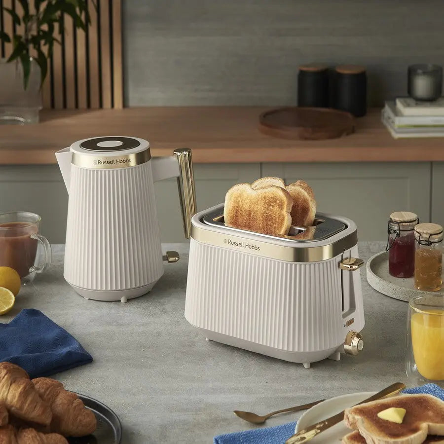 Kitchen scene with a toaster, kettle, and breakfast items on a countertop.