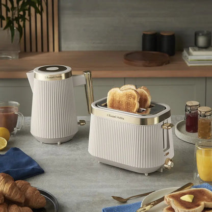Kitchen scene with a toaster, kettle, and breakfast items on a countertop.