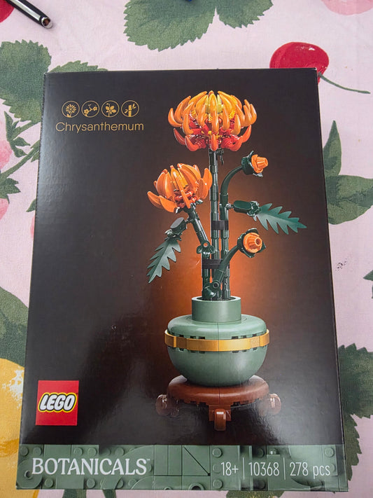 LEGO Botanicals Chrysanthemum building set box, showing the assembled orange chrysanthemum flower model on a dark background with LEGO branding and product details at the bottom.