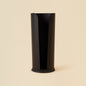 Black Cylindrical toilet paper holder against beige background
