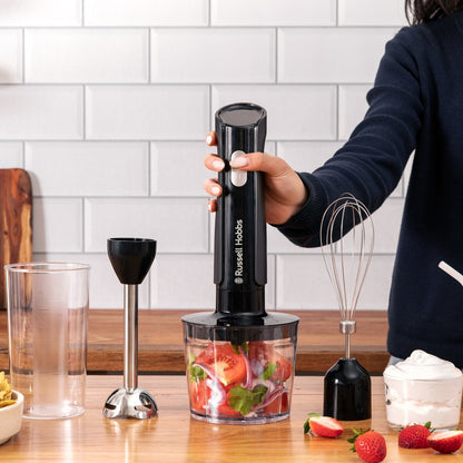Person using a Russell Hobbs blender on a kitchen counter with ingredients and tools around.