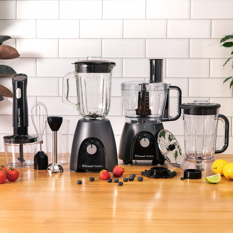 Set of kitchen appliances including blenders and a food processor on a wooden countertop with a tiled wall background.