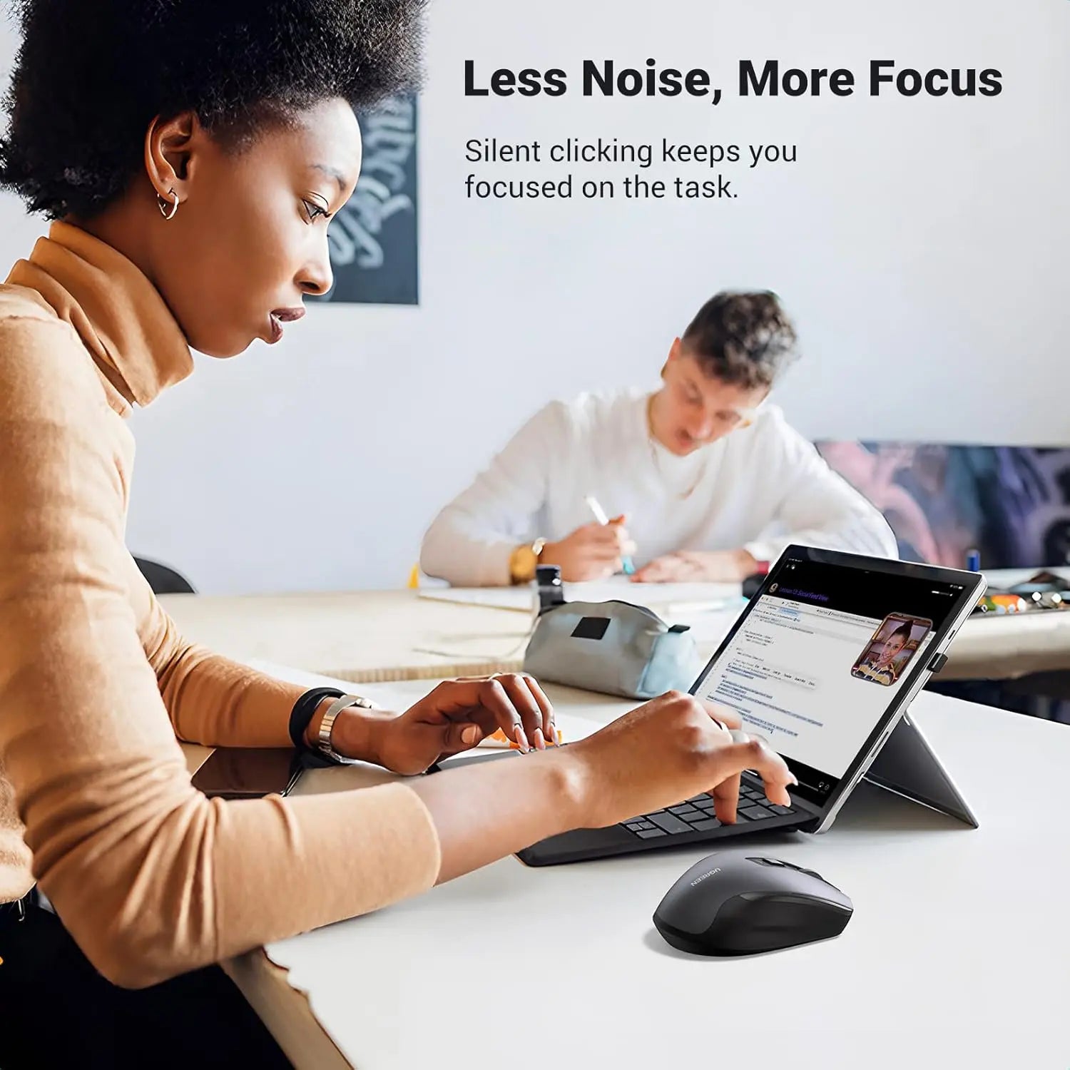 Person using a computer with a focus on noise reduction, sitting at a desk in a modern office setting.