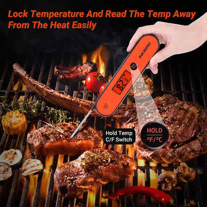 Digital thermometer being used on a grill with meat and vegetables.