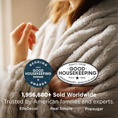 Person wrapped in a plush blanket with Good Housekeeping awards displayed.