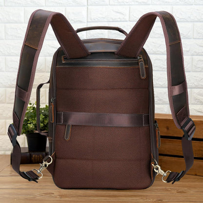 Brown backpack with leather straps on a wooden surface with a white brick wall background