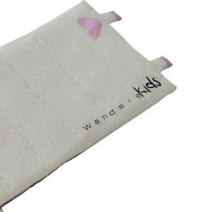 A close-up of a white padded fabric item, likely a children's cushion or pad, with stitched channels, small pink tabs at the corners, and the text 'wander kids' printed in black.