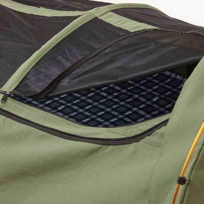 Close-up of a green camping tent with a black interior and plaid lining.