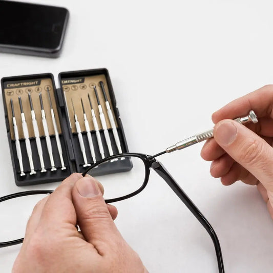 Person adjusting eyeglasses with a set of small tools on a white background