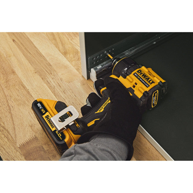 Person using a DEWALT power drill on a wooden floor.