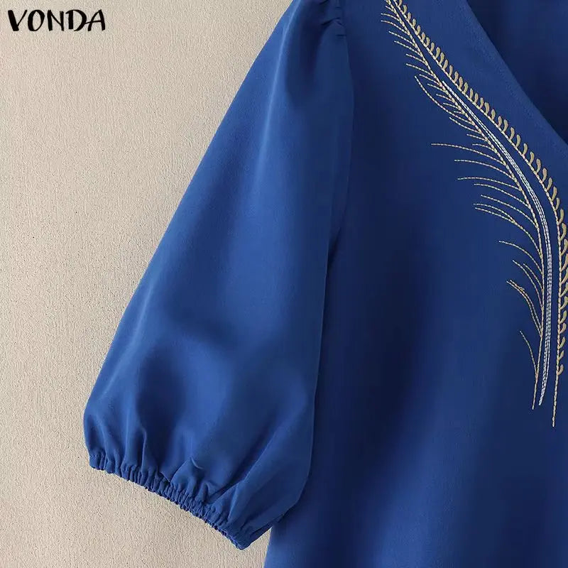 Blue blouse with embroidered design on a beige background, featuring the brand 'Vonda'.