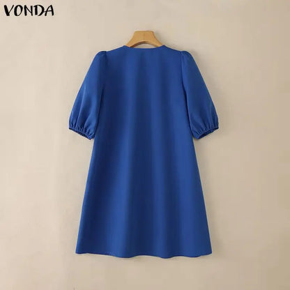 Blue dress on a hanger against a beige background with 'VONDA' branding.
