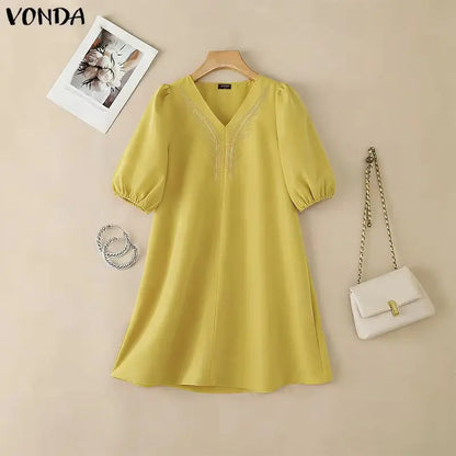 Yellow dress on a hanger with a white handbag and necklace on a beige background, featuring the brand 'Vonda'.