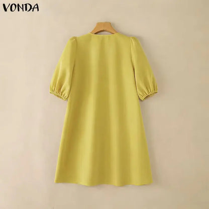 Yellow dress on a hanger against a beige background with 'Vonda' branding.