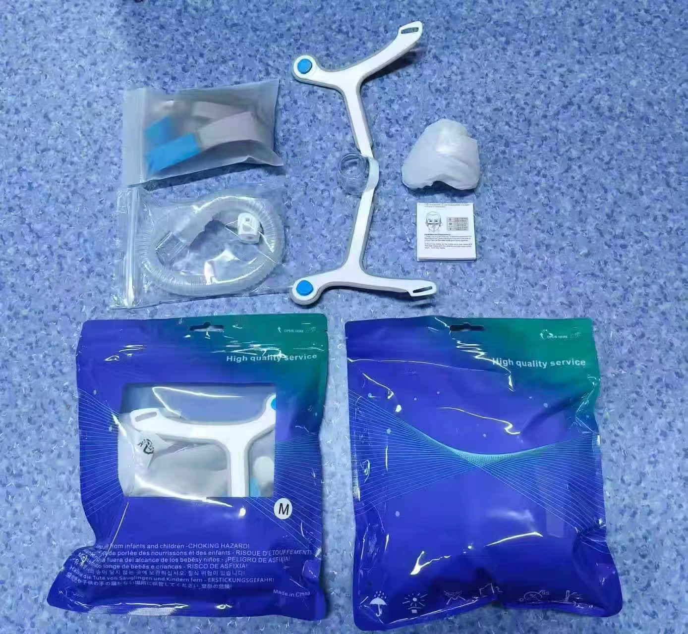 Set of dental tools including a white Y-shaped device, clear plastic components, and blue packaging on a textured blue surface.