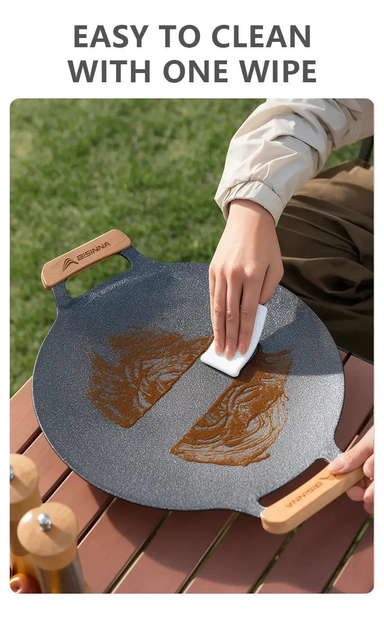 Person cleaning a wok with a cloth outdoors
