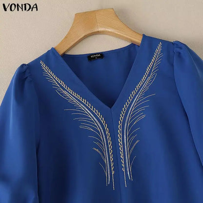 Blue blouse with embroidery on a wooden hanger against a beige background, featuring the brand 'Vonda'.
