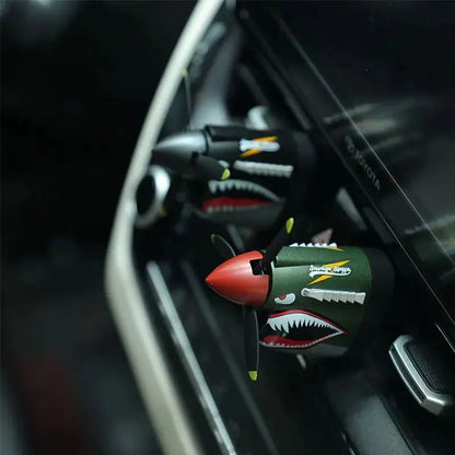 Car air freshener shaped like a shark with a red nose attached to a car's air vent.