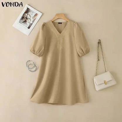 Beige dress on a hanger with a white handbag and necklace on a beige background, featuring the brand 'Vonda'.