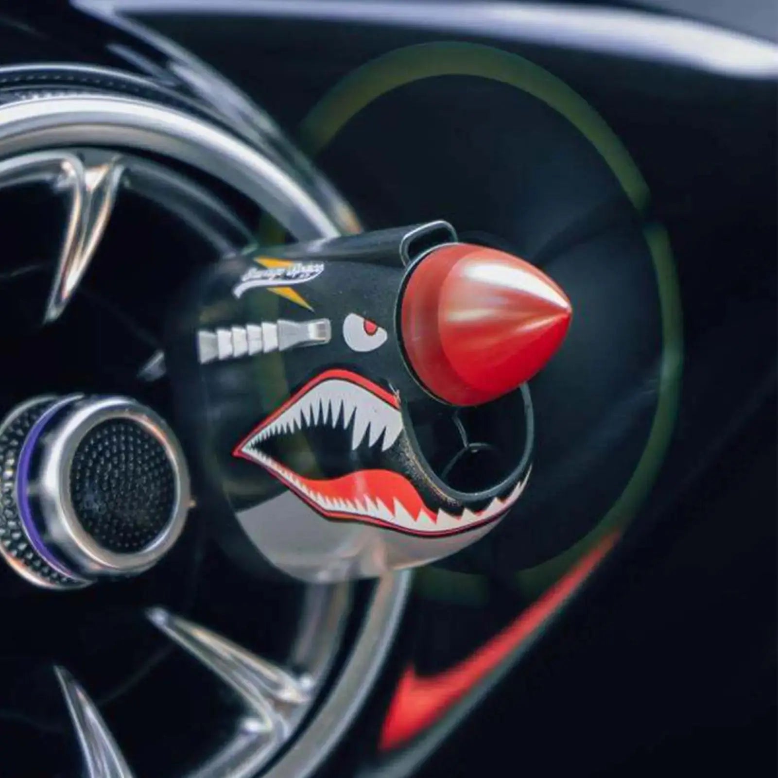 Car air freshener with shark design and red nose on a car dashboard
