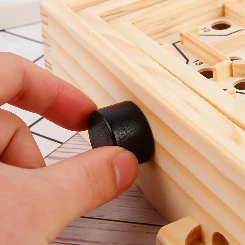 Hand placing a black cylindrical object into a wooden puzzle