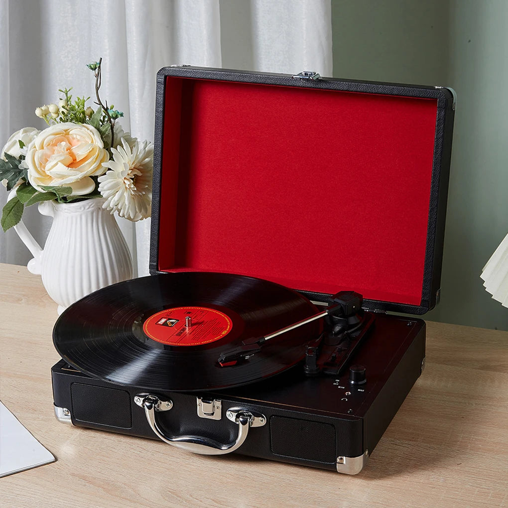 Portable Bluetooth vinyl record player with lid open styled beside flowers