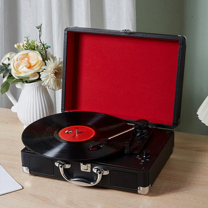 Portable Bluetooth vinyl record player with lid open styled beside flowers