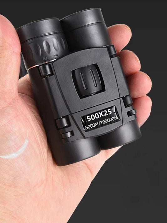 Black binoculars held in a hand against a black background