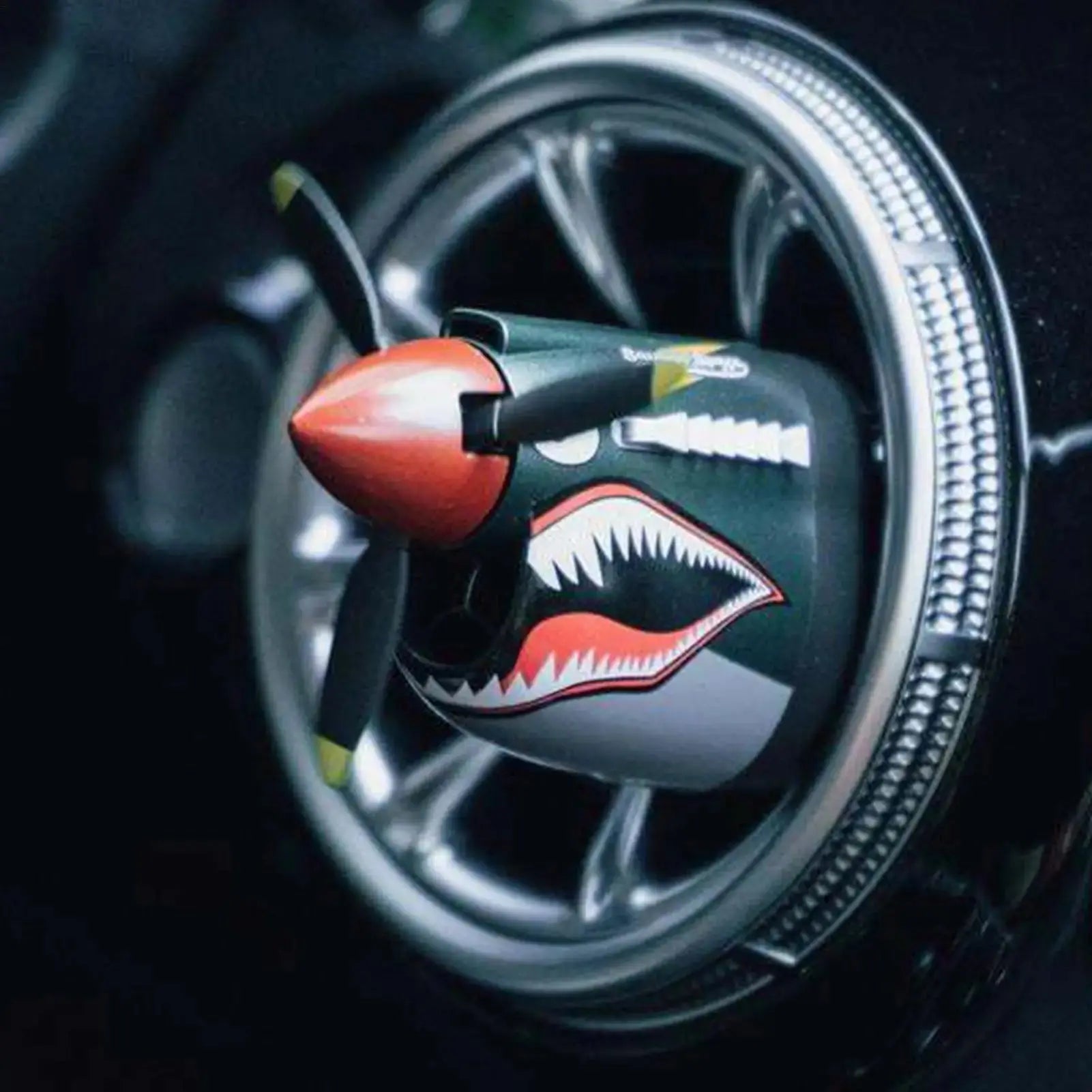 Close-up of a motorcycle wheel with a shark-themed air freshener.