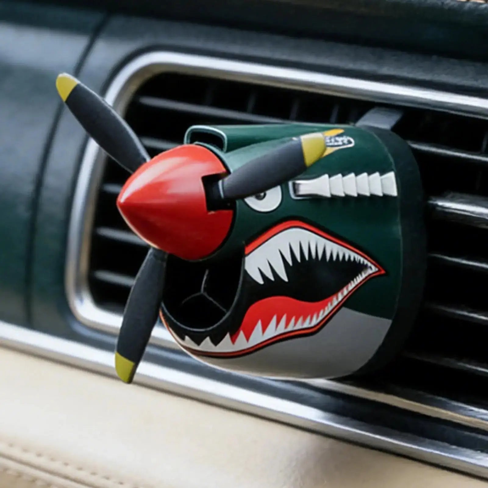 Car air freshener shaped like a shark with a propeller on a car vent.
