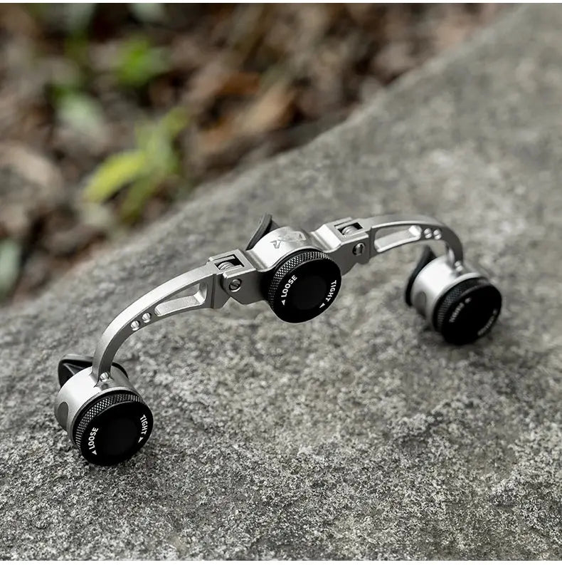 Metallic camera lens with adjustable dials on a stone surface