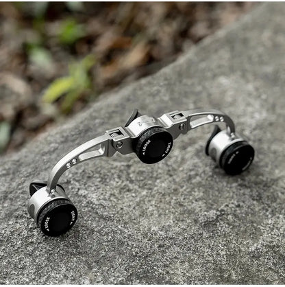 Metallic camera lens with adjustable dials on a stone surface
