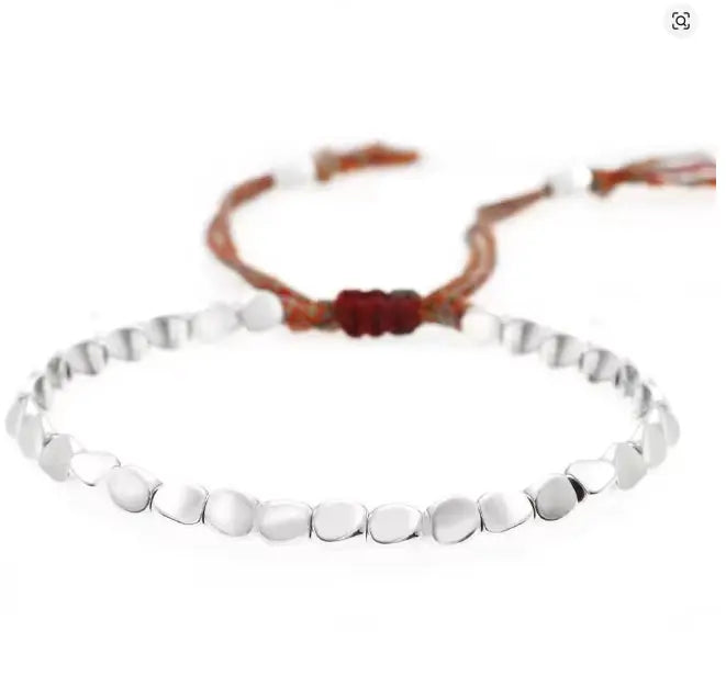 Silver beaded bracelet with a brown cord on a white background