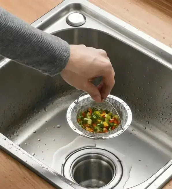 Person using a strainer with vegetables over a kitchen sink