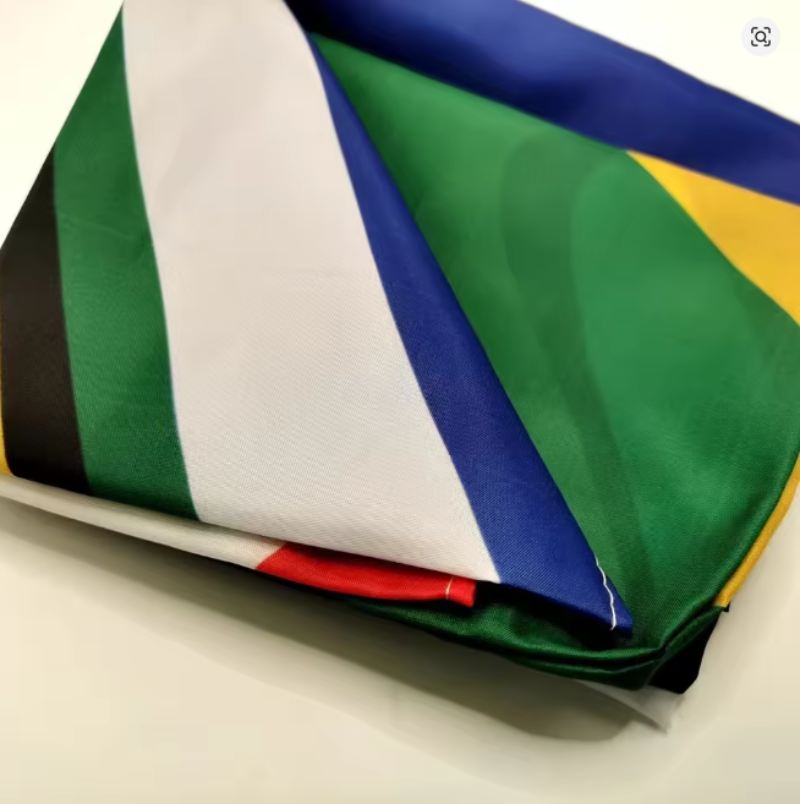 A folded fabric accessory, likely a scarf or pocket square, featuring the South African flag design with its characteristic green, white, blue, yellow, black, and red diagonal bands.