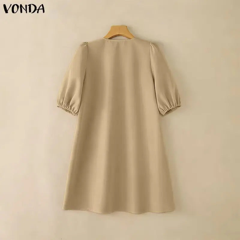 Beige dress on a wooden hanger against a beige background with 'VONDA' branding.