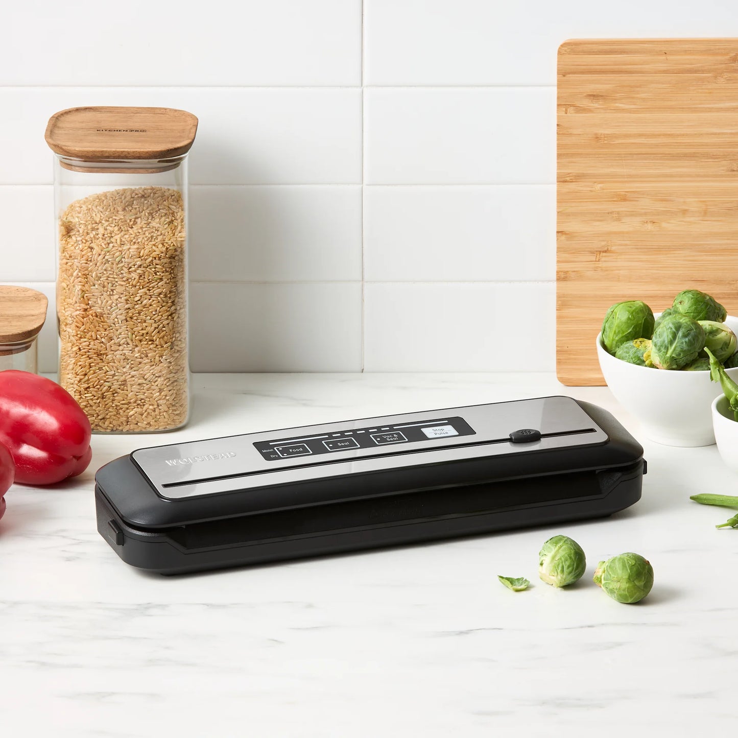 Vacuum sealer on a kitchen counter with vegetables and grains in the background