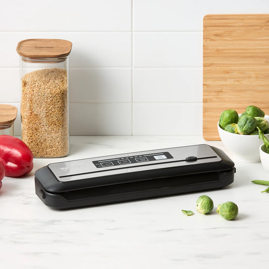 Vacuum sealer on a kitchen counter with vegetables and grains in the background