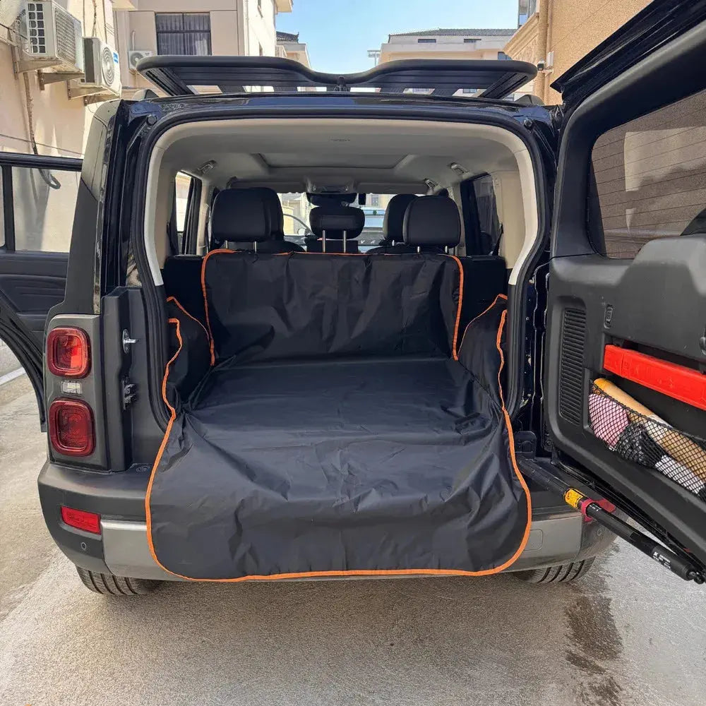 Open car trunk with a black and orange cargo cover on a street.