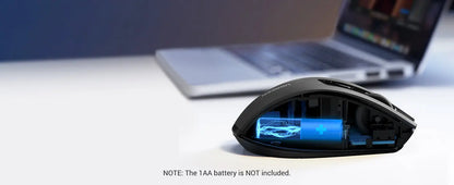 Gaming mouse with TAA battery compartment on a desk with a laptop in the background
