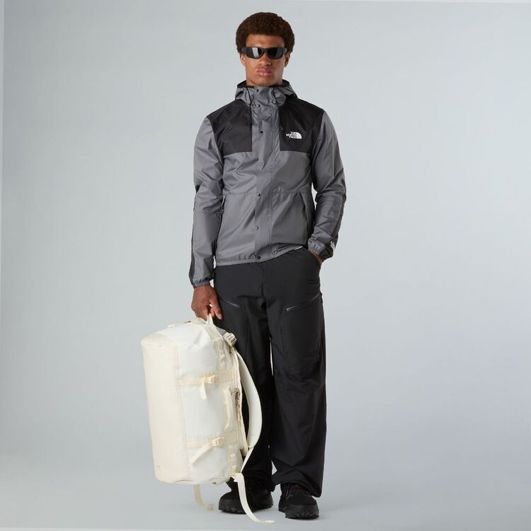 Person wearing a gray and black jacket with a white backpack on a light gray background