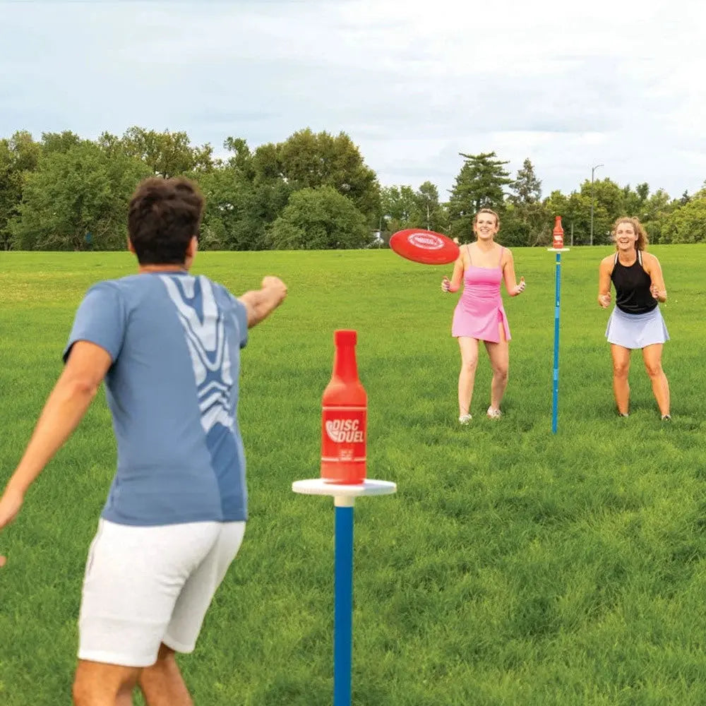 People playing a game with bottles on stands in a grassy field