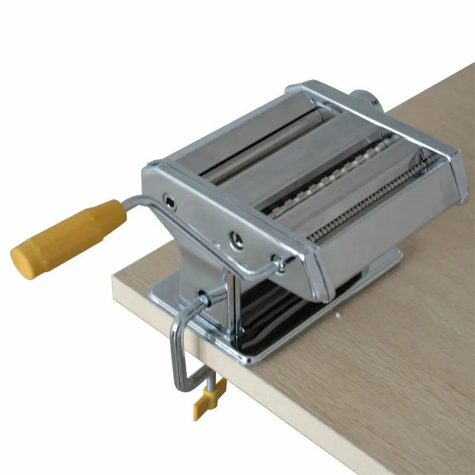 Metal pasta maker on a wooden surface with a white background