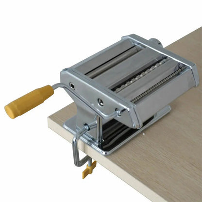 Metal pasta maker on a wooden surface with a white background